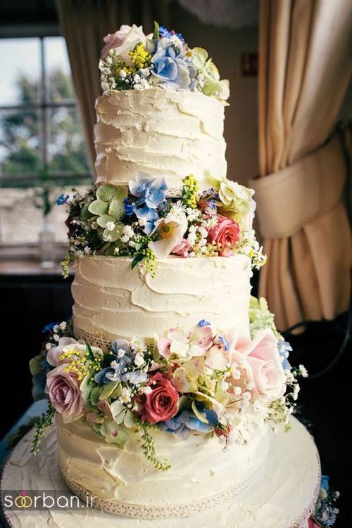 کیک عروسی با روکش خامه و گل های طبیعی رنگارنگ و شکوفه