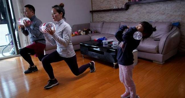 خانواده ای مشغول تمرین ورزشی آنلاین در خانه شان در شانگهای چین 
